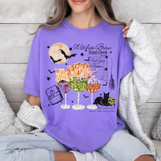 Three Witches Brew DTF Heat Transfer, colorful Halloween-themed design on purple t-shirt featuring bats, a moon, witch's poison bottles, a broom, and a black cat with a skull.