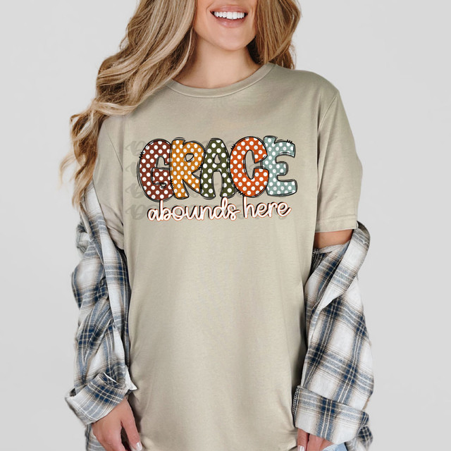 Grace Abounds Here Dots DTF Heat Transfer, colorful dotted letters spelling 'GRACE' on a T-shirt worn by a smiling woman.