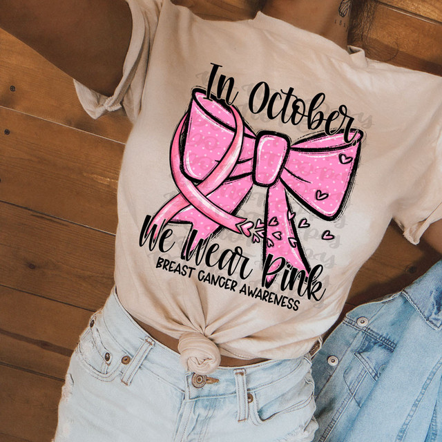 In October We Wear Pink Breast Cancer Awareness DTF Heat Transfer on a T-shirt, pink bow with hearts, promoting breast cancer awareness.