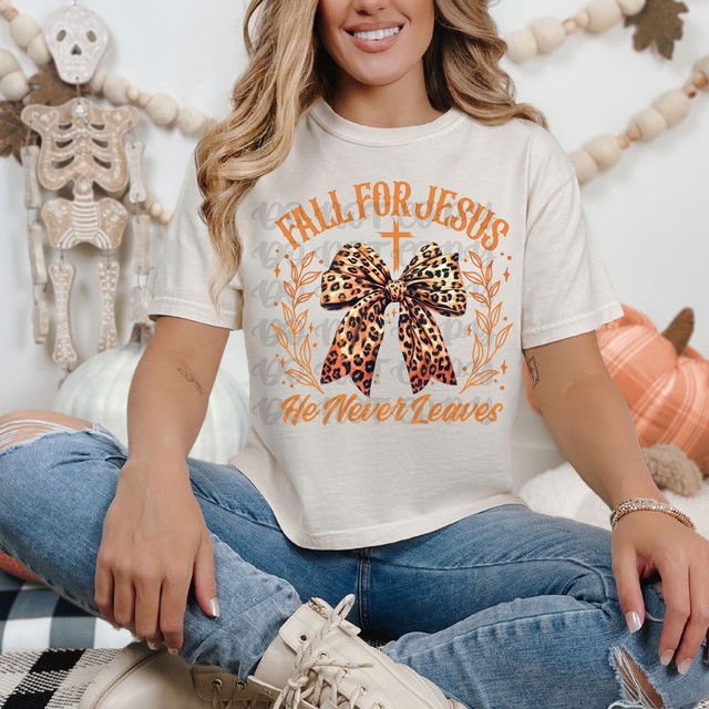 Fall For Jesus He Never Leaves Leopard Bow DTF Heat Transfer, woman wearing a T-shirt with leopard print bow and fall-themed design.