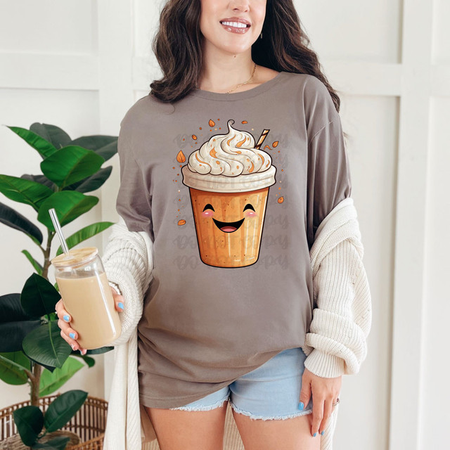 Pumpkin Spice Frappe Happy Face DTF Heat Transfer, cheerful cartoon depiction of a pumpkin spice frappe with whipped cream and a straw on a woman's t-shirt.