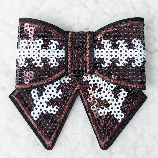 Football Sequin Bow Hat/Pocket Patch, decorative bow-shaped patch with black, white, and bronze sequins for accessories and clothing embellishments.