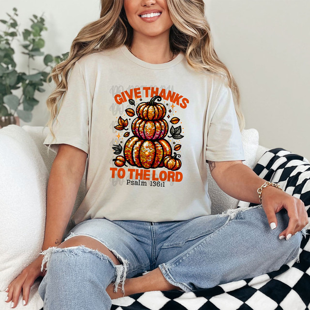 Give Thanks To the Lord Faux Sequins DTF Heat Transfer, a woman wearing a beige t-shirt with a colorful sequin pumpkin design and the text 'Give Thanks To the Lord' inspired by Psalm 136:1.