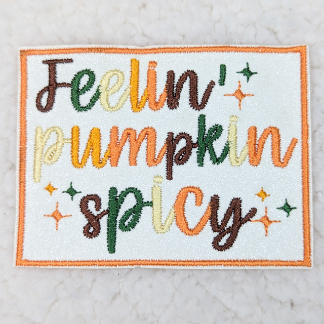 Feelin' Pumpkin Spicy Embroidered HAT/POCKET Patch, colorful embroidered patch featuring the phrase 'Feelin' Pumpkin Spicy' with stars on a white background.