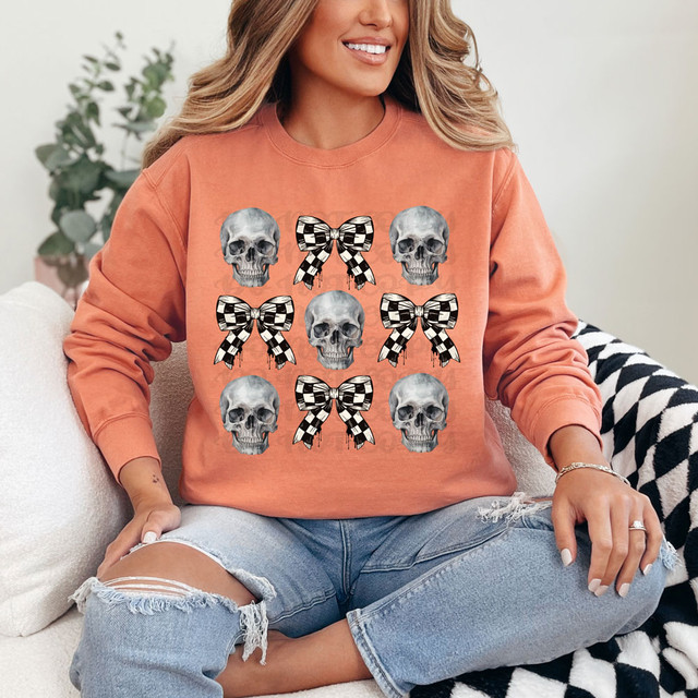 Skull Checker Bow DTF Heat Transfer, design of 3 skulls and 3 checkered bows on a woman's sweatshirt.