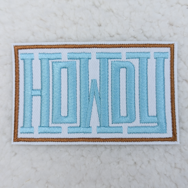 Howdy BLUE Embroidered HAT/POCKET Patch, a rectangular patch featuring the word 'Howdy' embroidered in blue thread with a brown border, designed to be sewn onto hats or pockets for decoration.