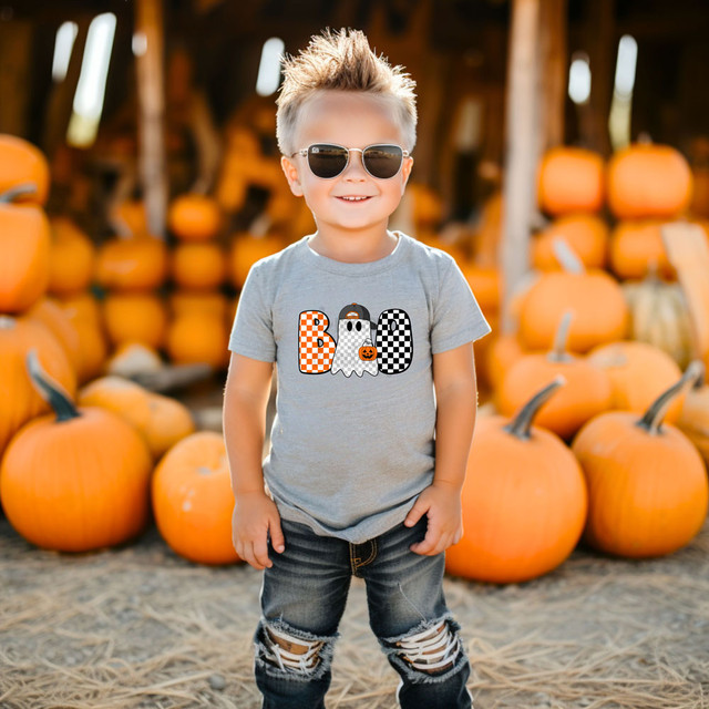 Boo Checkered Ghost DTF Heat Transfer, Halloween-themed design on a child's t-shirt with pumpkins in the background.