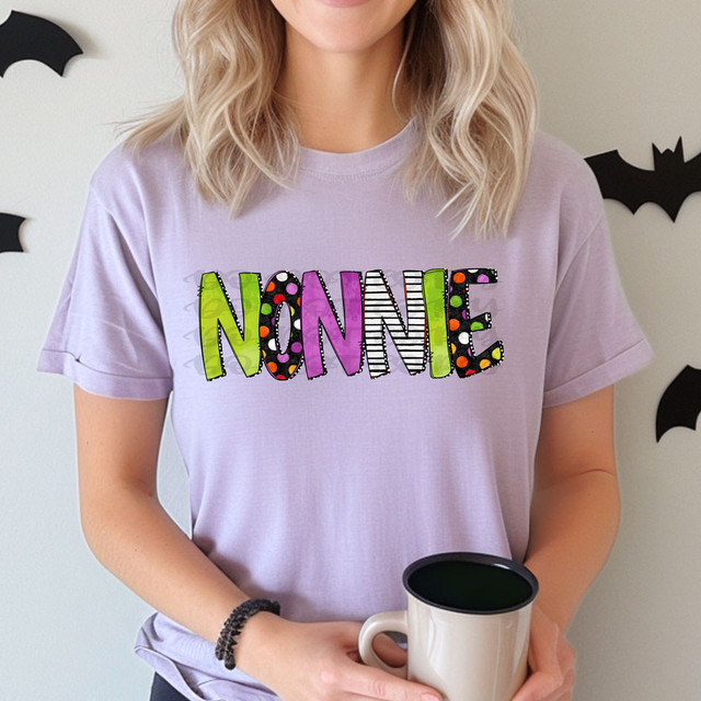 Nonnie Halloween Letters DTF Heat Transfer, colorful and festive Halloween-themed text on a woman's purple T-shirt.