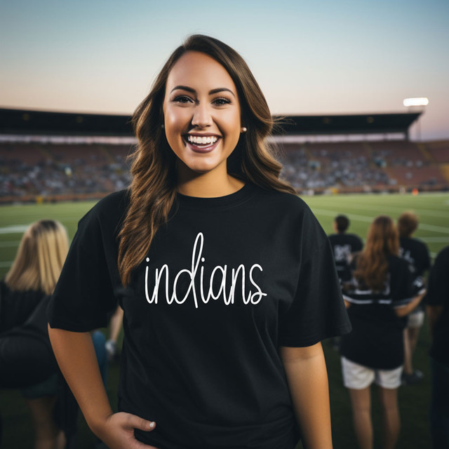 Indians Mascot WHITE DTF Heat Transfer, a photo of a young woman wearing a black t-shirt with 'indians' written on it, smiling at a sports stadium.