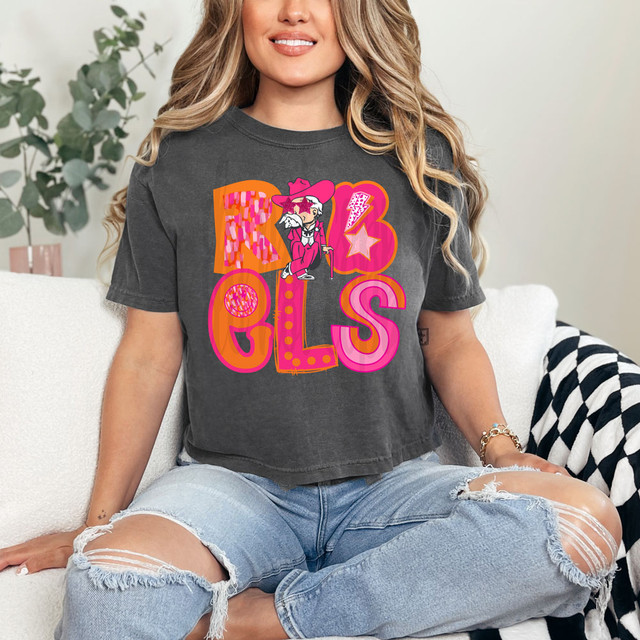 Rebels Pink/Orange Block DTF Heat Transfer, close-up of a woman wearing a T-shirt with a colorful graphic design featuring the word 'REBELS' and a cartoon character.