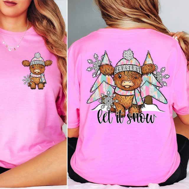Let It Snow Highlander Cow SET DTF Heat Transfer, pink T-shirt featuring a cute Highlander cow wearing a winter hat and scarf with winter trees and snowflakes in the background.