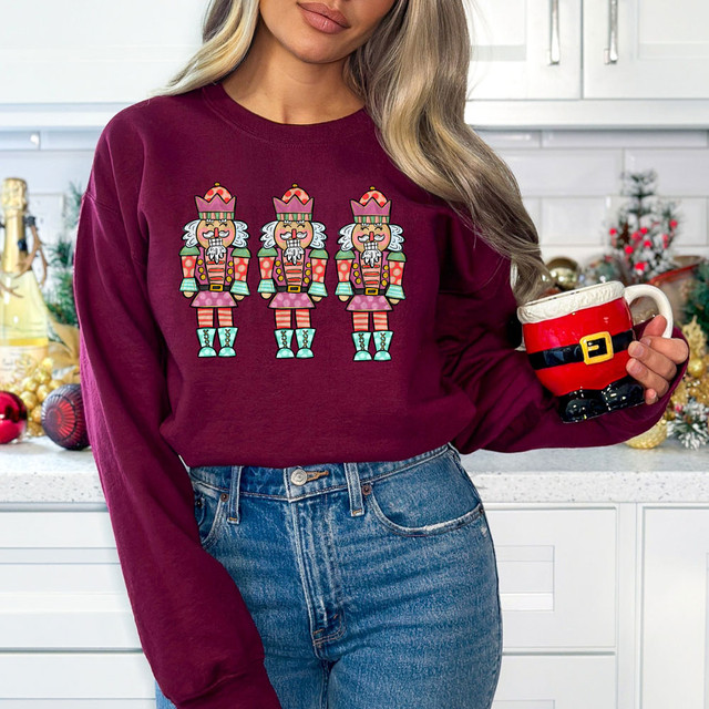 Nutcracker Trio DTF Heat Transfer, festive holiday design featuring three colorful nutcracker soldiers on a maroon sweatshirt.