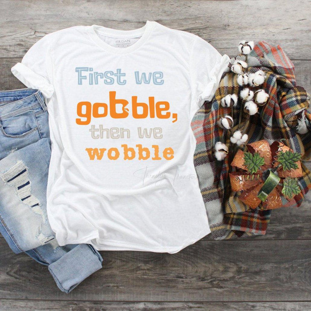 First we gobble then we wobble Sublimation Transfer T-shirt, white T-shirt with text design, paired with ripped jeans and fall-themed accessories.
