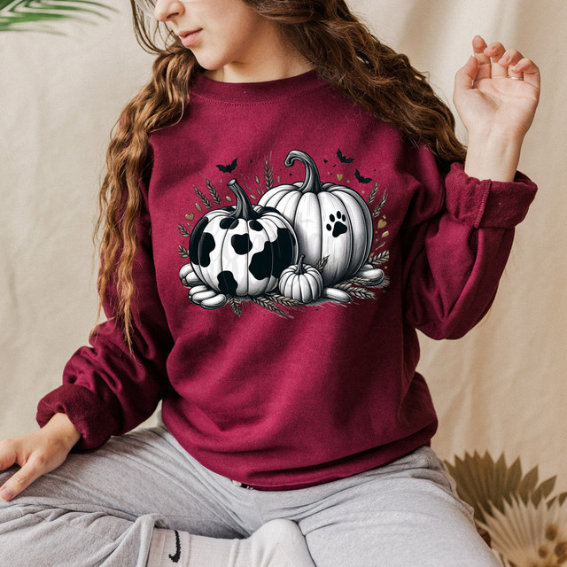 Black and White Pumpkins DTF Heat Transfer, Halloween themed pumpkins with black and white spotted designs on a burgundy sweatshirt worn by a woman.