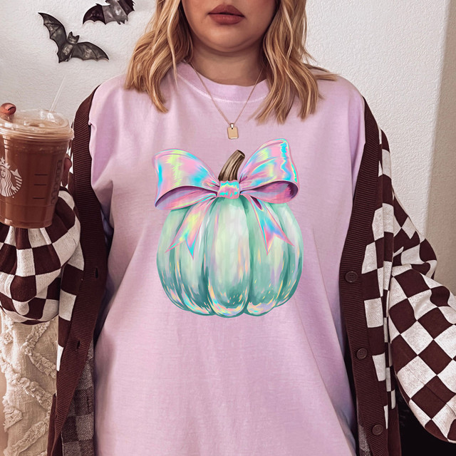 Iridescent Bow Pumpkin DTF Heat Transfer, holographic pumpkin with a large iridescent bow on top, on a person wearing a pink t-shirt.
