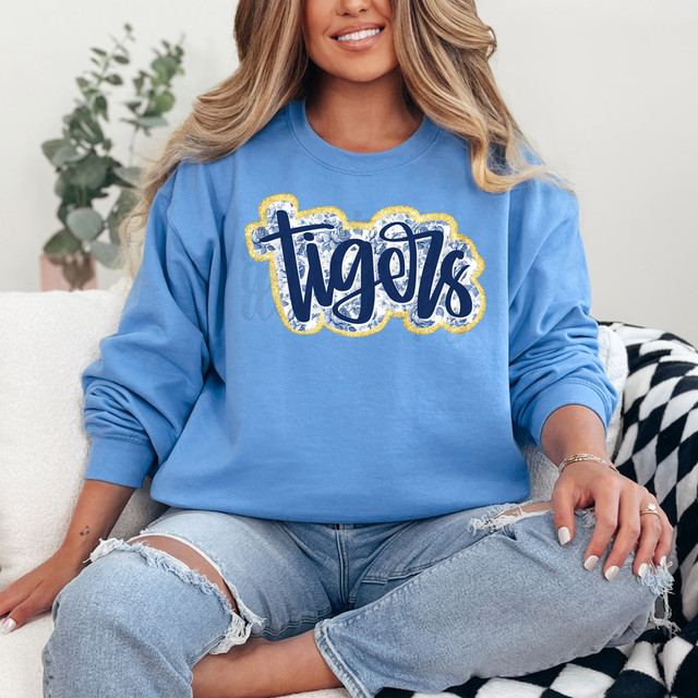 Tigers Blue Floral Mascot Faux Glitter DTF Heat Transfer, image of a woman wearing a blue sweatshirt with a glittery tiger logo design.