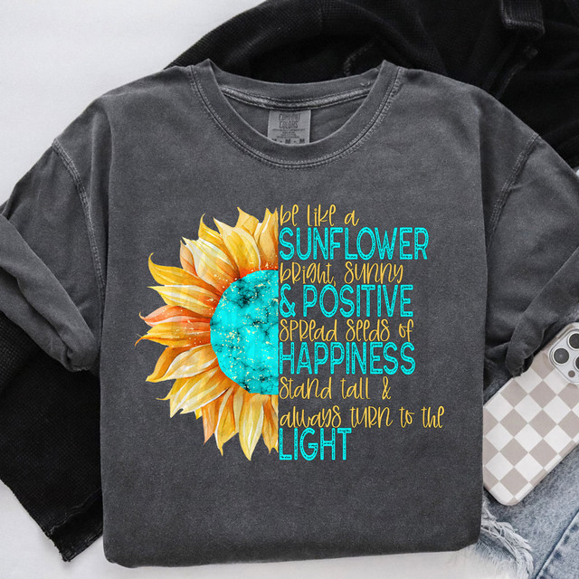 Be Like A Sunflower DTF Heat Transfer, graphic of a sunflower with a vibrant blue center and yellow petals, with inspirational quote in colorful text.