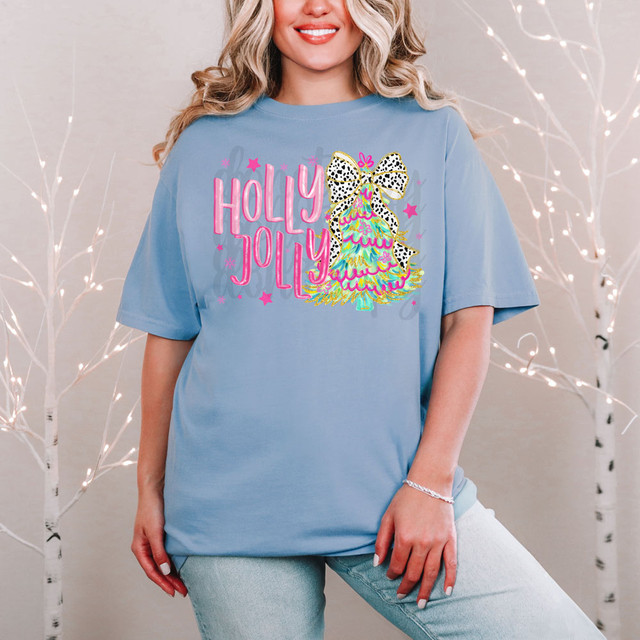 Holly Jolly Coquette Christmas Tree DTF Heat Transfer, colorful glittery Christmas tree graphic with a bow and holiday decorations on a light blue T-shirt.