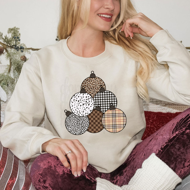 Patterned Ornaments DTF Heat Transfer, girl wearing sweatshirt with Christmas ornament pattern featuring various animal print and plaid designs.