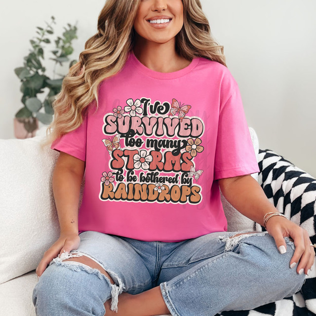 I've Survived Too Many Storms To Be Bothered By Raindrops, pink T-shirt with floral and butterfly design, DTF heat transfer.