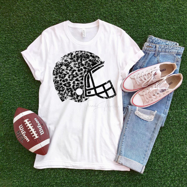 White leopard football helmet, sublimation transfer, printed on a white t-shirt with jeans and sneakers, on green grass background.