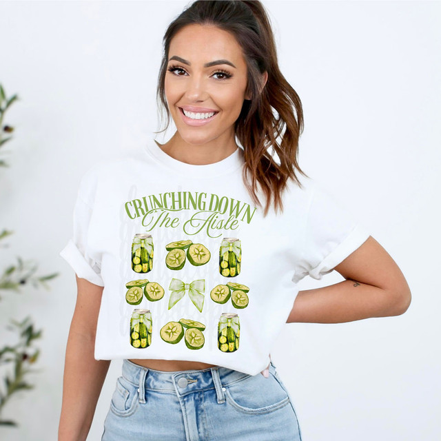 Crunching Down The Aisle DTF Heat Transfer, a woman wearing a white t-shirt with a green pickle-themed design and text, showcasing a custom heat transfer product.