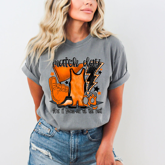 Match Day Give It Your All On The Mat Orange/Black DTF Heat Transfer, a vibrant graphic design on a gray t-shirt featuring wrestling-themed elements like a wrestling singlet, foam fingers, a whistle, and lightning bolts.