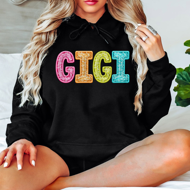 Bright Groovy Gigi Faux Sequins DTF Heat Transfer, a woman wearing a black hoodie with multicolored sequined GIGI letters on the front.