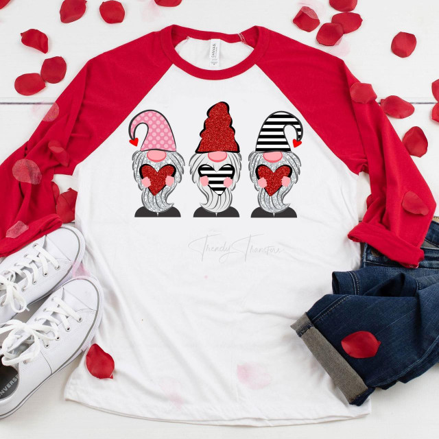 Glitter Gnome Valentine Sublimation Transfer, a graphic design featuring three gnomes with glitter beards holding hearts, on a white and red raglan t-shirt.
