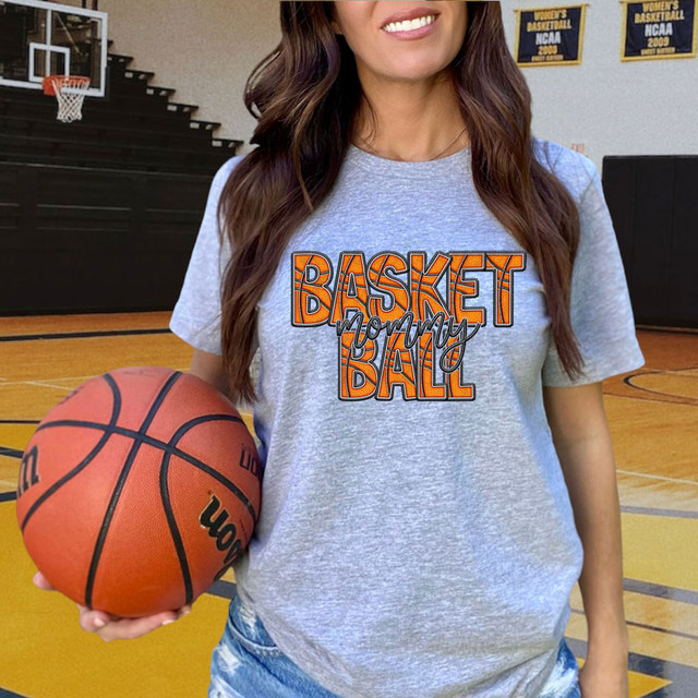 Basket Mommy Basketball Faux Embroidery DTF Heat Transfer, woman wearing a t-shirt with basketball-themed embroidery in a gymnasium.