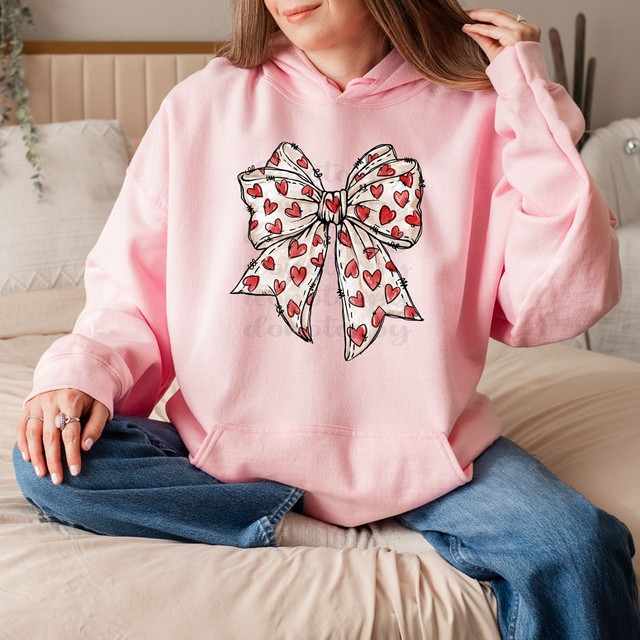 Hand Drawn Red Heart Bow DTF Heat Transfer, woman wearing a pink hoodie with a large bow design featuring red hearts.