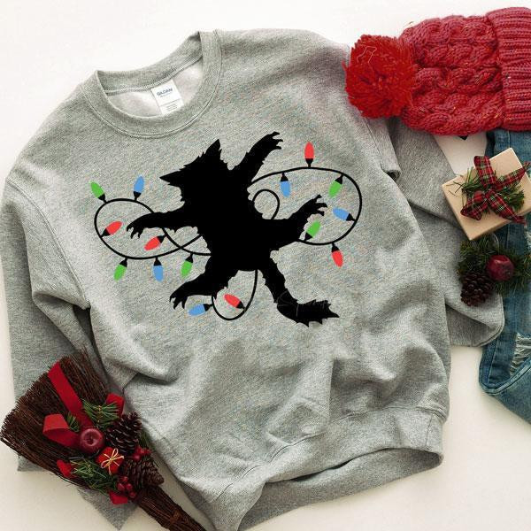 Fried Pussycat Christmas Vacation Screen Print Heat Transfer, black cat silhouette wrapped in colorful holiday string lights on a gray sweatshirt.