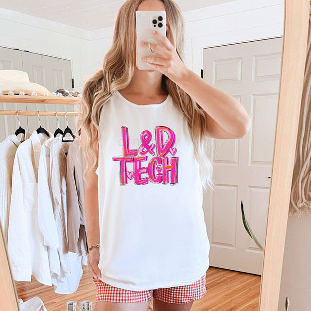 Painted L&D Tech DTF Heat Transfer, pink and purple neon style graphic design on a white sleeveless top worn by a woman in front of a mirror.