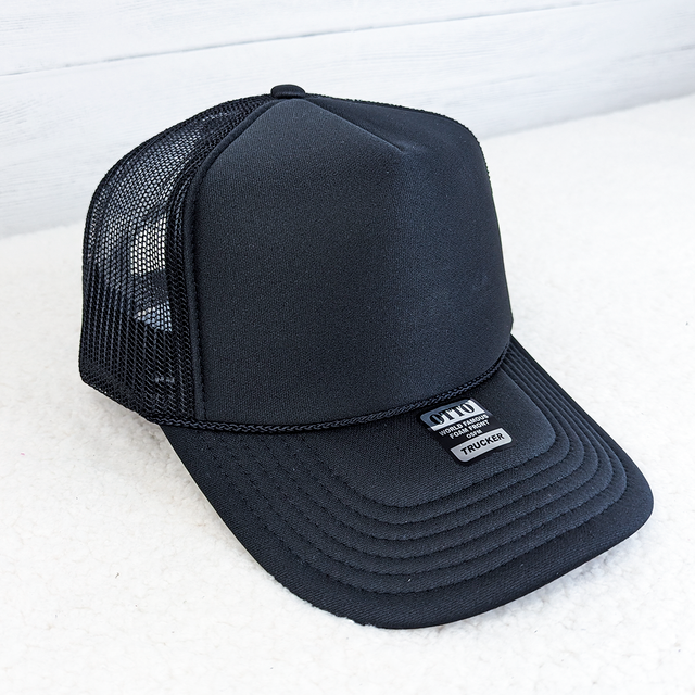 Black Foam Trucker Hat, a sleek black mesh and foam cap with structured front panel and curved brim.