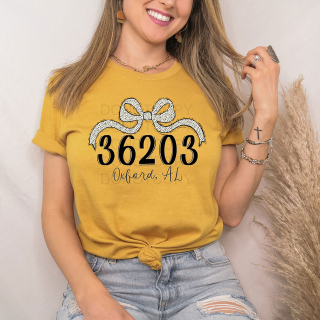 Oxford, AL Zip Code Bow DTF Heat Transfer on a yellow T-shirt, with a bow design and the zip code '36203' along with 'Oxford, AL' text.