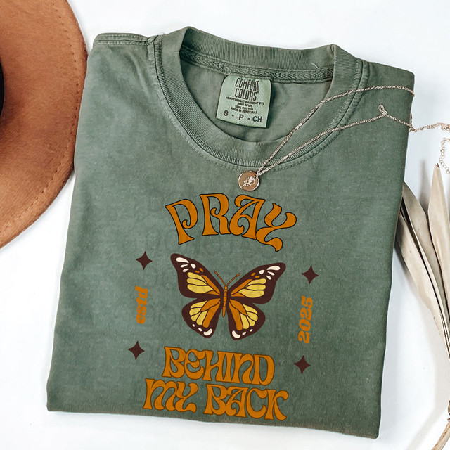 Pray Behind My Back DTF Heat Transfer, green t-shirt with butterfly design and text, featuring a necklace on top of the shirt.