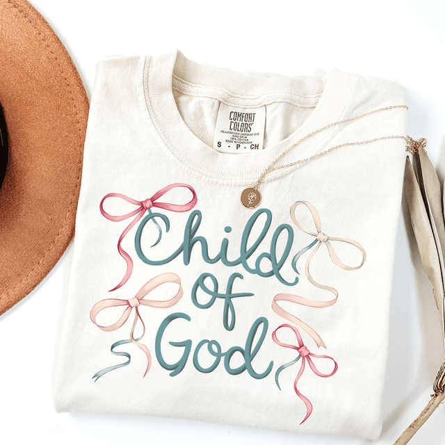 Child Of God Bow DTF Heat Transfer, white T-shirt with biblical quote and colorful ribbon bows design.