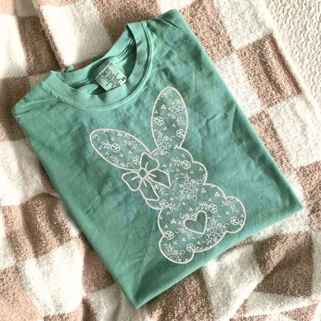 Easter Lace Bunny DTF Heat Transfer, a white lace-style bunny design with floral patterns and a small heart on a teal t-shirt.