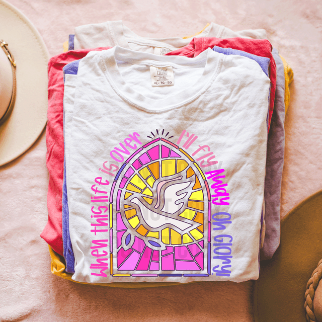 When This Life Is Over I'll Fly Away DTF Heat Transfer T-shirt, white t-shirt with a colorful stained-glass style dove design and uplifting message.