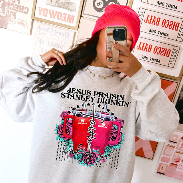 Faith Kind Of Girl DTF Heat Transfer, a woman wearing a sweatshirt with a colorful graphic design and text, taking a selfie.