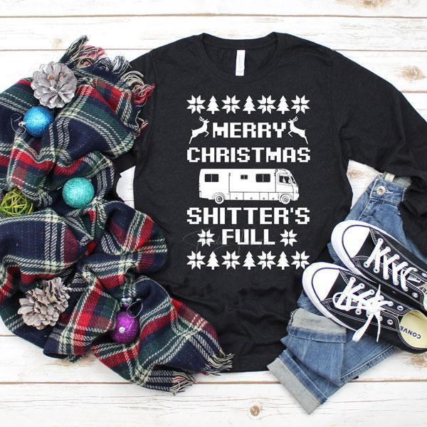 Merry Christmas Shitter's Full Christmas Vacation Screen Print Transfer, black long sleeve shirt with holiday-themed graphics and text, surrounded by holiday decorations and casual accessories.