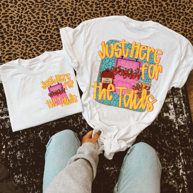 Just Here For The Tails SET DTF Heat Transfer, white T-shirt with colorful printed design featuring a pink cooler with crawfish and newspaper, and the phrase 'Just Here For The Tails' in bold yellow and pink lettering.
