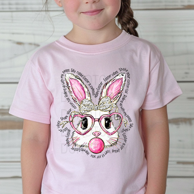 Bubblegum Bunny Easter Sayings DTF Heat Transfer, cute bunny wearing pink glasses and a polka dot bow with Easter-themed text around it on a girl's pink T-shirt.