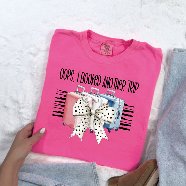 Oops, I Booked Another Trip DTF Heat Transfer, pink T-shirt with graphic of 3 suitcases and a polka dot bow, ready for travel-themed fashion or gift.