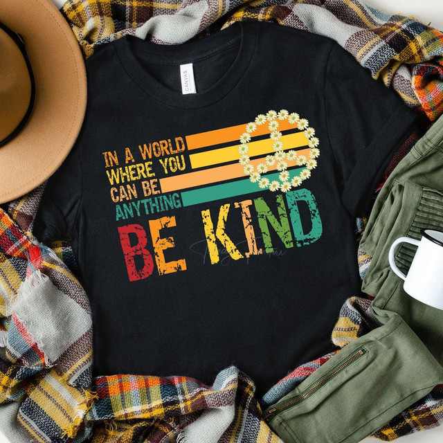 In A World Where You Can Be Anything Be Kind Screen Print Heat Transfer T-Shirt, black T-shirt with colorful text and daisy circle design that promotes kindness and positivity.
