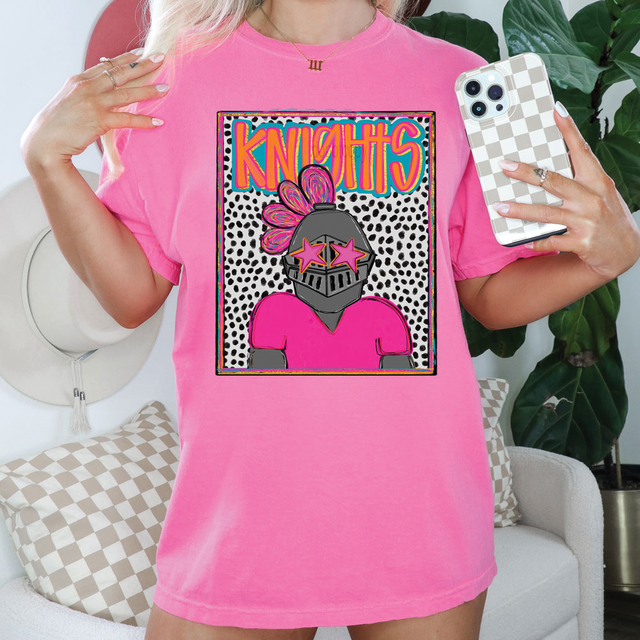 Knights Colorful Mascot DTF Heat Transfer, vibrant colorful knight mascot graphic on a pink t-shirt, featuring a cartoon knight with star-shaped sunglasses and a feathered helmet in a fun, pop art style.