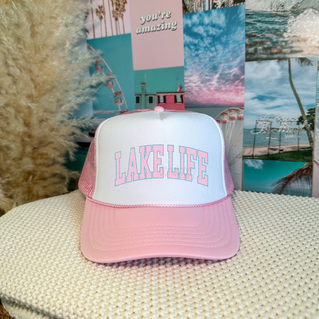 Lake Life Varsity Style DTF Heat Transfer, pink and white trucker cap with layered text graphics, popular summer and beach-themed accessory.