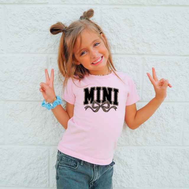 Mini Leopard Bow DTF Heat Transfer, girl wearing pink t-shirt with mini leopard bow design.