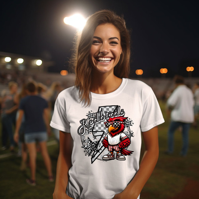 Red Birds Checkered Bolt DTF Heat Transfer, vibrant red bird cartoon graphic on a white T-shirt worn by smiling woman at outdoor event.