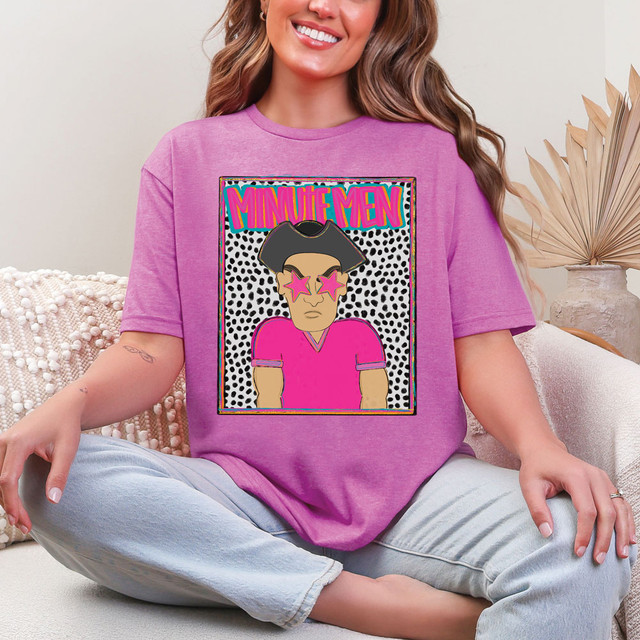 Minute Men Colorful Mascot DTF Heat Transfer, vibrant pink and black cartoon mascot design on a purple t-shirt worn by a smiling woman.